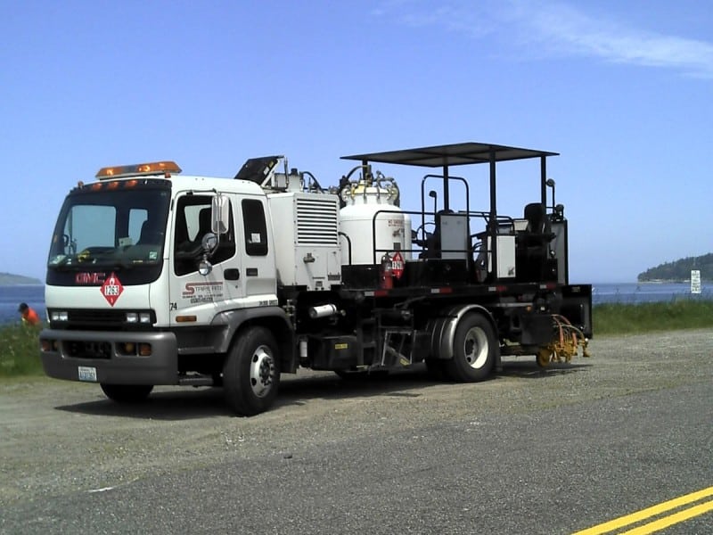 A large work truck that belongs to the company Stripe Rite parked on the side of a road